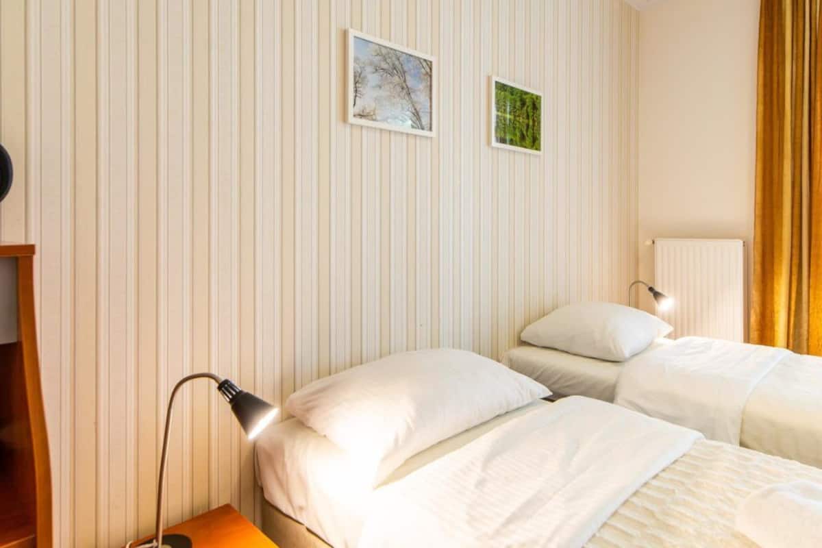 Ein Hotelzimmer mit zwei Betten, einem Nachttisch, einer Lampe und zwei gerahmten Bildern an der Wand.