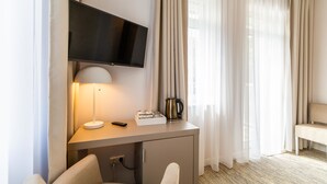 A hotel room with a desk, a television, a lamp, a coffee maker, and a chair. - Ośrodek Wypoczynkowy Wiga (Kolobrzeg)