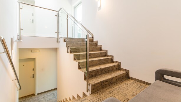 A modern staircase with glass railings and wooden steps leading to an upper floor. - Ośrodek Wypoczynkowy Wiga (Kolobrzeg)