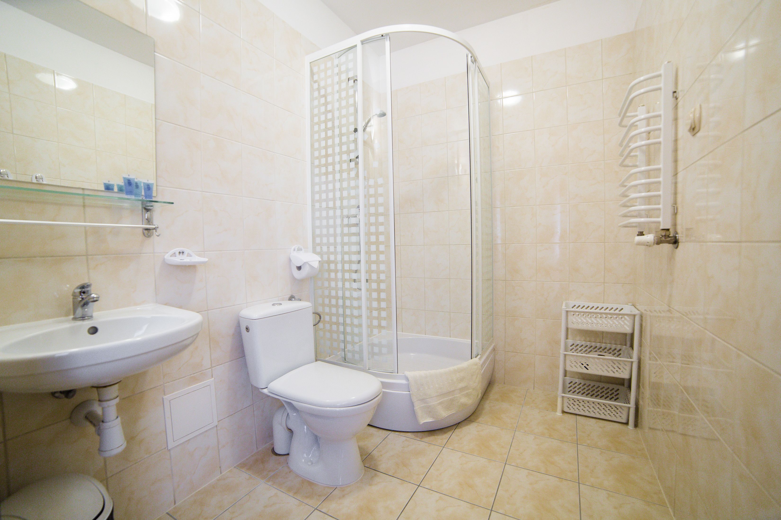 A bathroom with a sink, toilet, shower, and a towel rack.