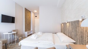 A hotel room with a bed, a desk, a chair, a TV, and a wall-mounted light fixture. - Ośrodek Wypoczynkowy Wiga (Kolobrzeg)