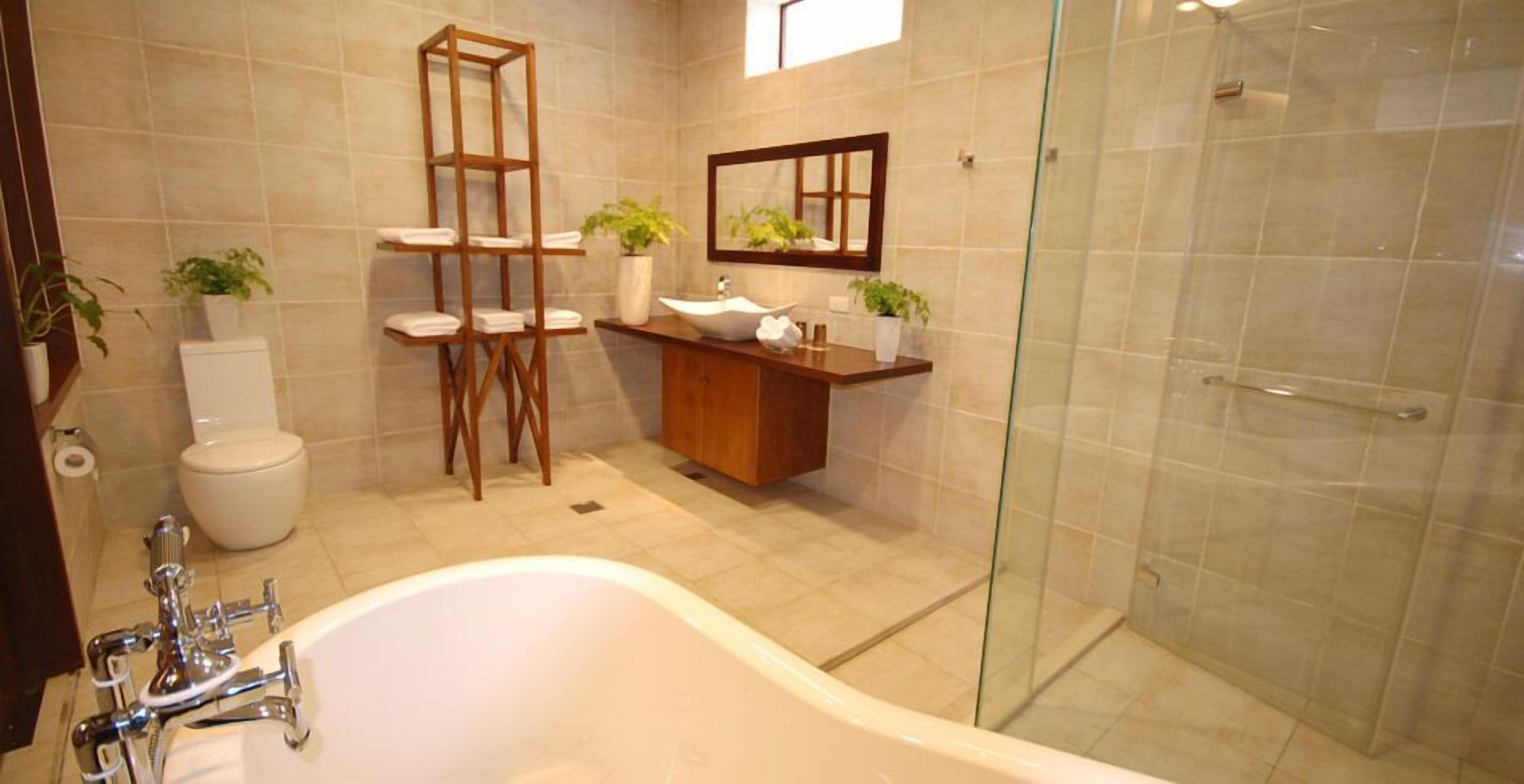 A modern bathroom with a freestanding bathtub, a glass-enclosed shower, a wooden vanity, and a toilet.