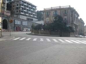 A street intersection with a crosswalk, a building with a sign reading "parquet moquette," and another sign that says "barberia." - Midnight in Genova (Genoa)