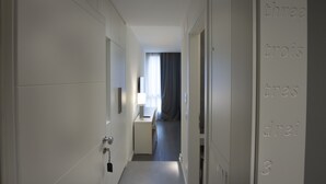 A narrow hallway with a desk and a lamp, leading to a room with a window and curtains. - Midnight in Genova (Genoa)
