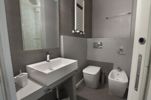 A modern bathroom with a large sink, toilet, bidet, and a mirror. - Midnight in Genova (Genoa)