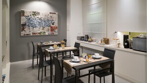 A modern dining area with a long table, chairs, and a coffee station. - Midnight in Genova (Genoa)