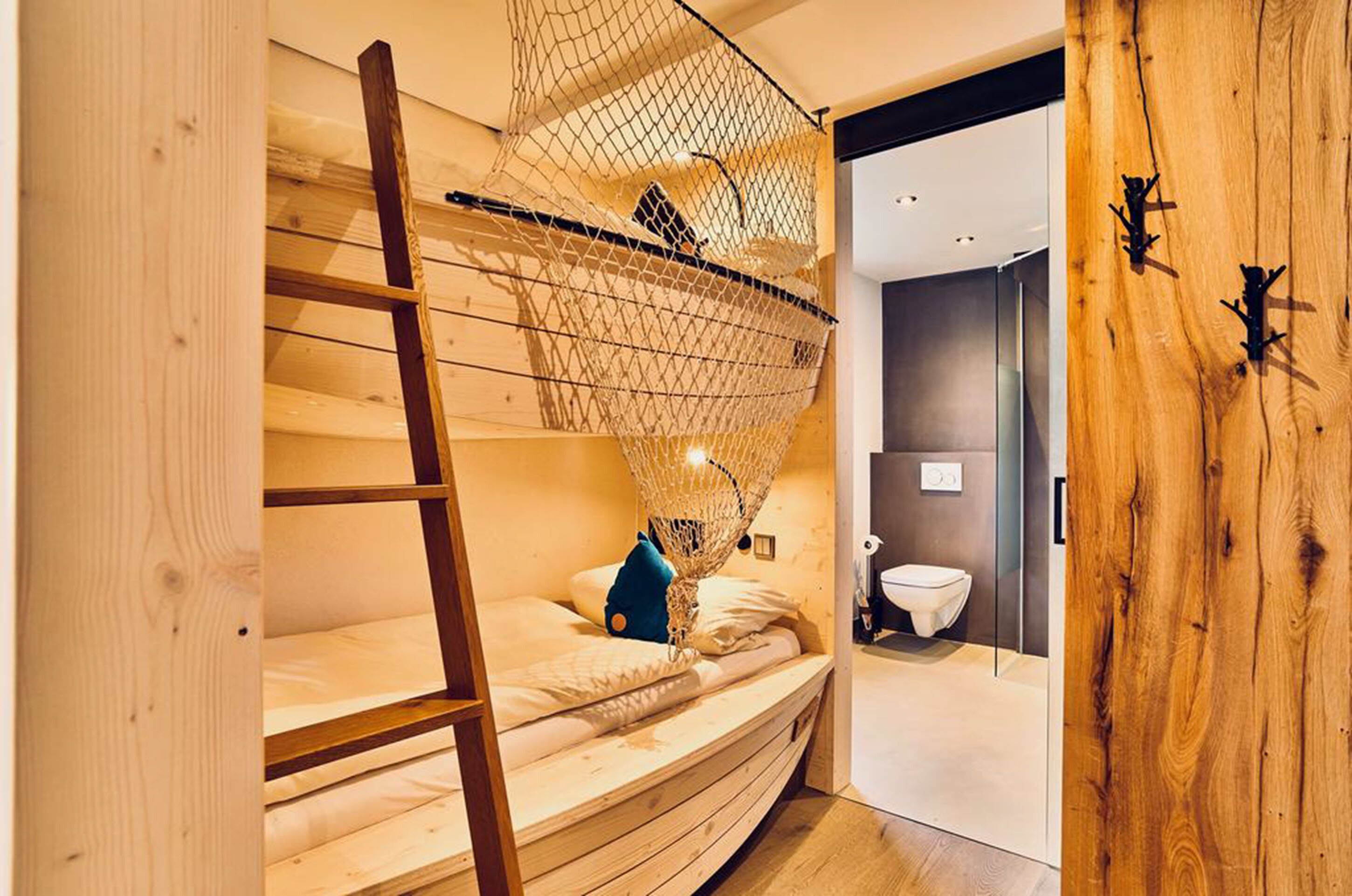 A bunk bed with a net canopy, a ladder, and a blue pillow.