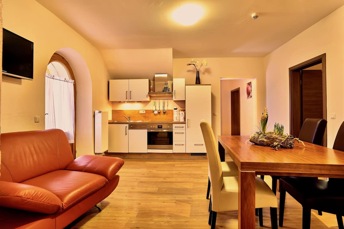 A compact kitchen with white cabinets, a wooden countertop, and a dining table with chairs.