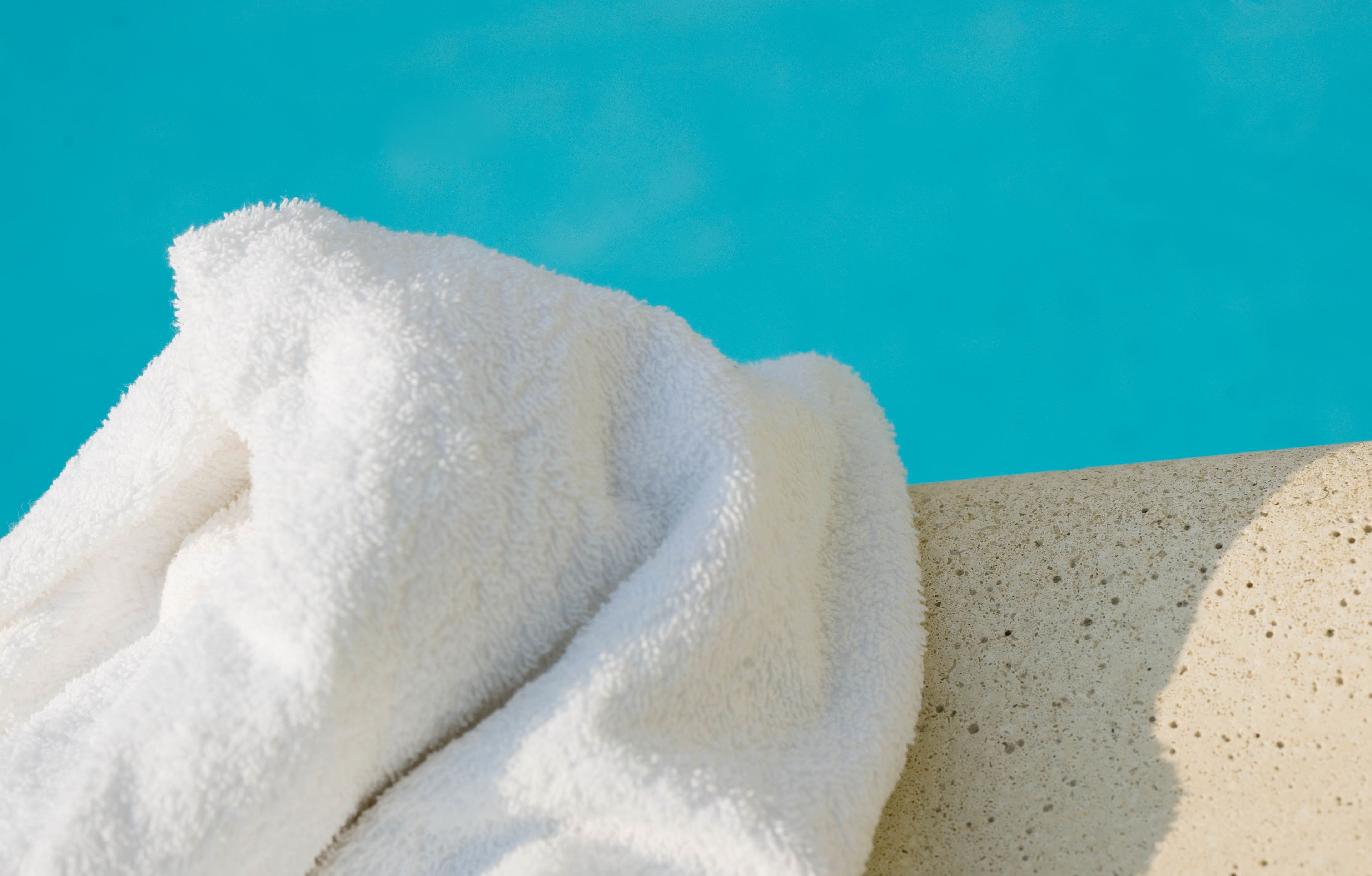 A white towel on a textured surface with a clear blue sky in the background.