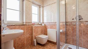 Ein Badezimmer mit Waschbecken, Toilette, Dusche und einem Fenster.