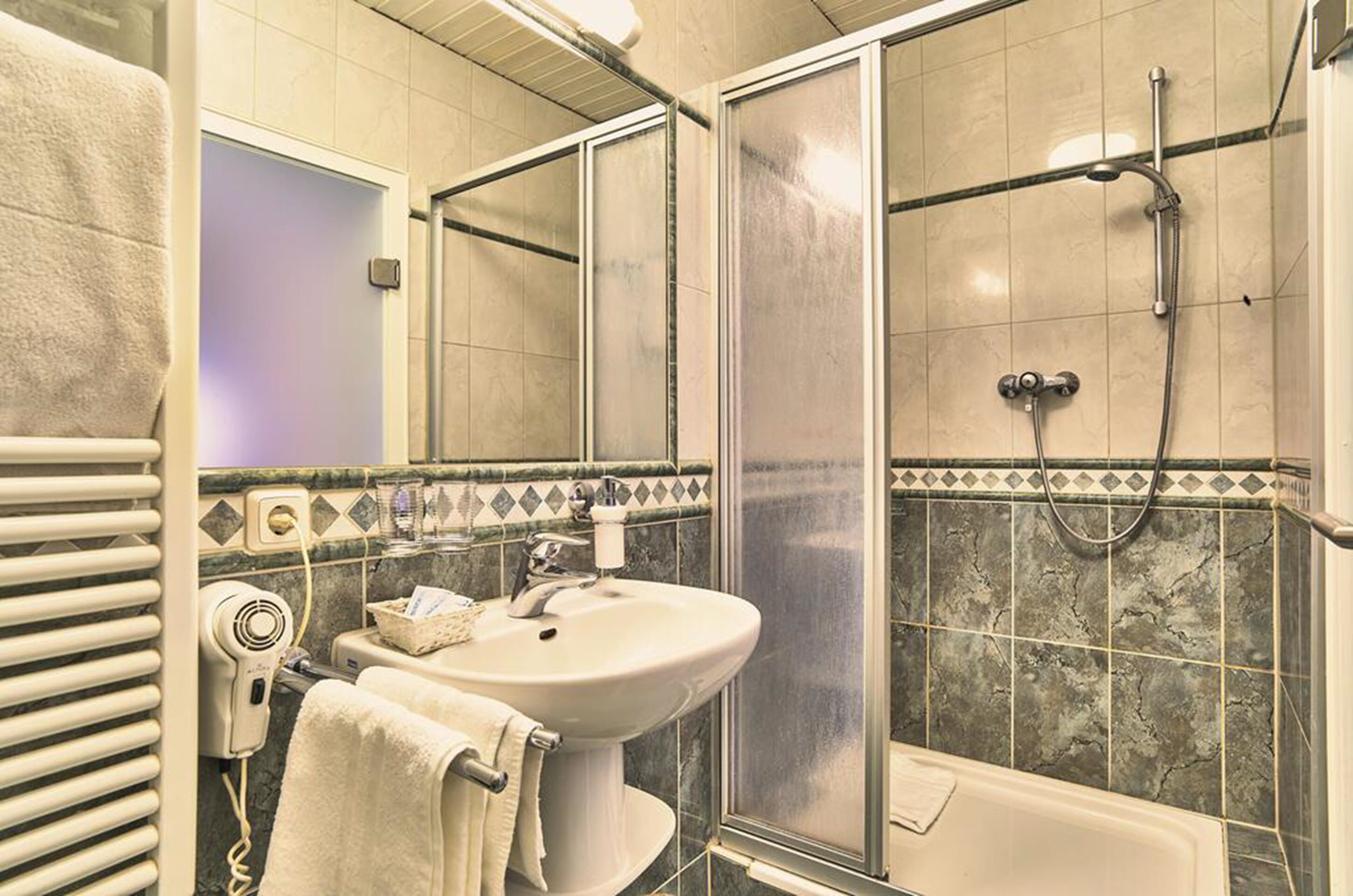 Ein Badezimmer mit Dusche, Waschbecken und Handtuchhalter.