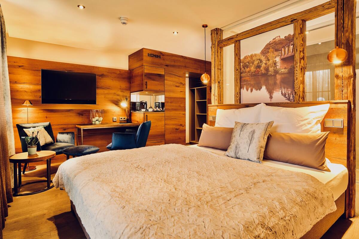 A modern hotel room with a large bed, a desk, and a TV.