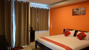 Una habitación de hotel con una cama grande, paredes anaranjadas y un cuadro de una playa.