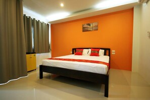 A hotel room with a bed, curtains, a painting on the wall, and a small yellow cabinet. - Phangan Guest House - Hostel (Ko Pha-ngan)