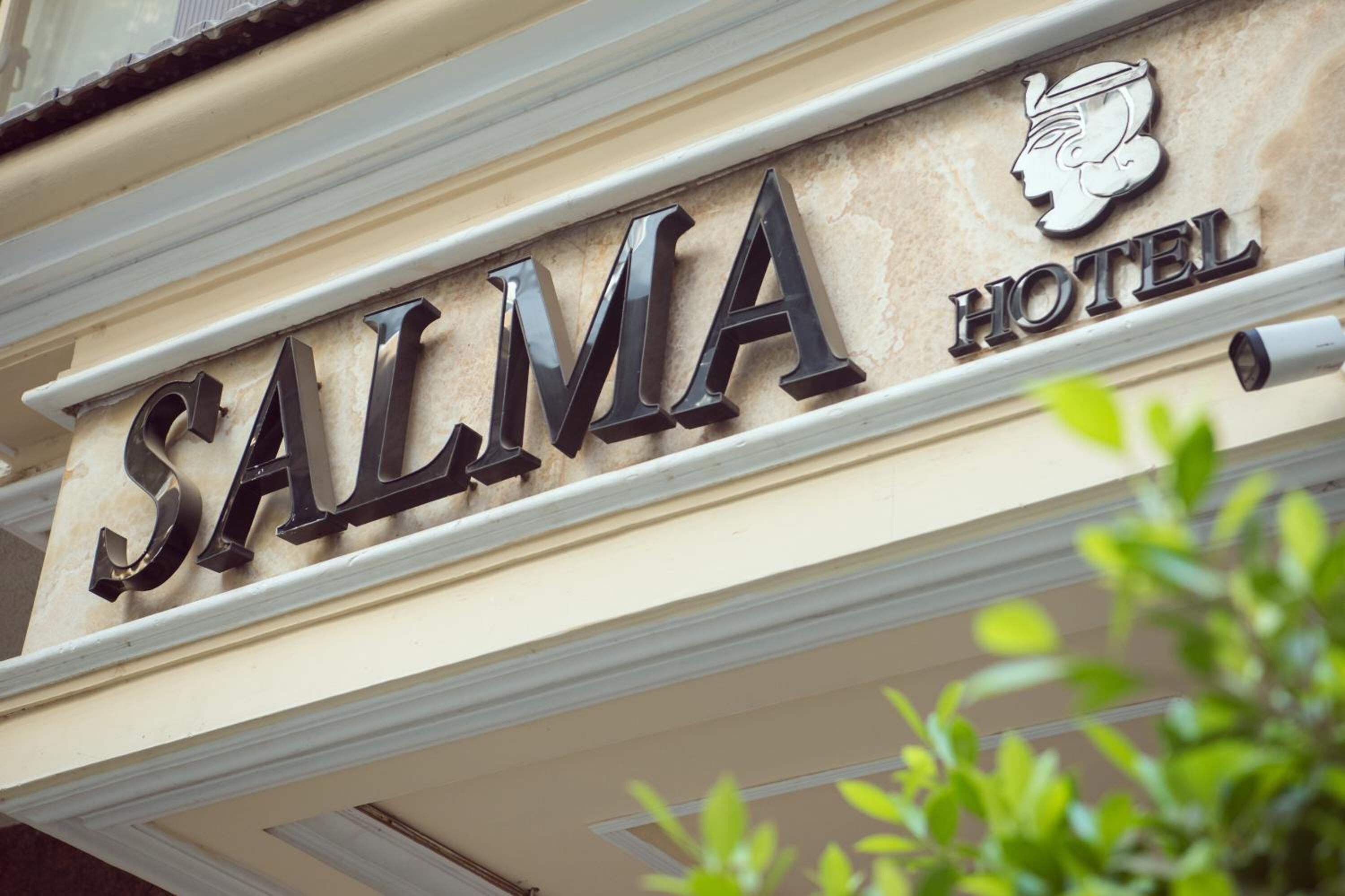 A hotel sign with the name "SALMA HOTEL" and a classical female head motif.