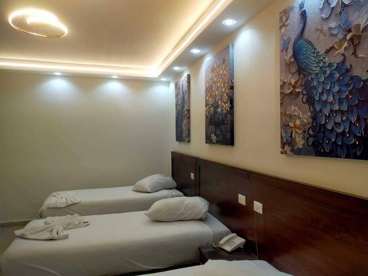 Una habitación de hotel con dos camas individuales, cabecero de madera y teléfono instalado en la pared.