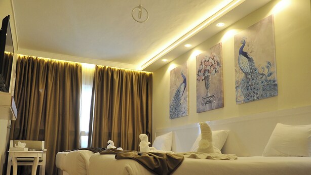 A hotel room with a bed, a small table, and a chair. There are curtains on the windows and artwork on the walls. - Salma Hotel (Giza)
