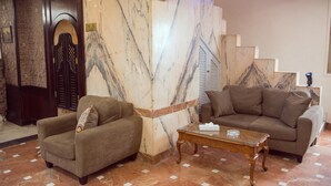 A lobby with a marble wall, a wooden door, a sofa, a coffee table, and a staircase. - Salma Hotel (Giza)