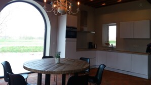 Een moderne keuken met een ronde eettafel, zwarte stoelen en een kroonluchter.