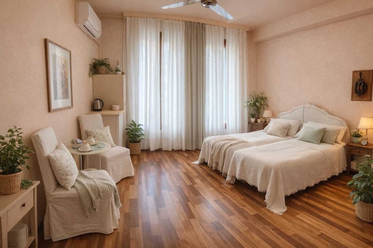Habitación de hotel con dos camas, una silla, una mesita y un ventilador de techo.