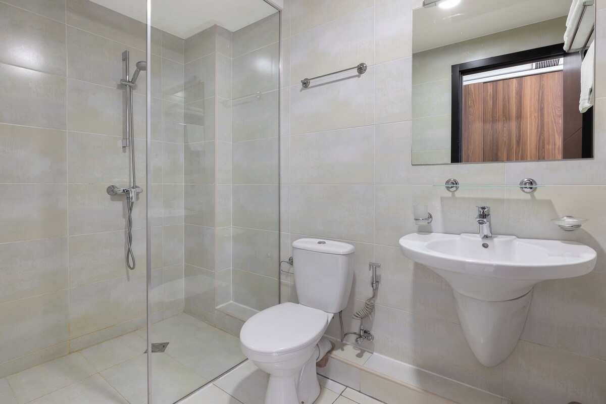 A modern bathroom with a glass-enclosed shower, a white toilet, and a large sink.