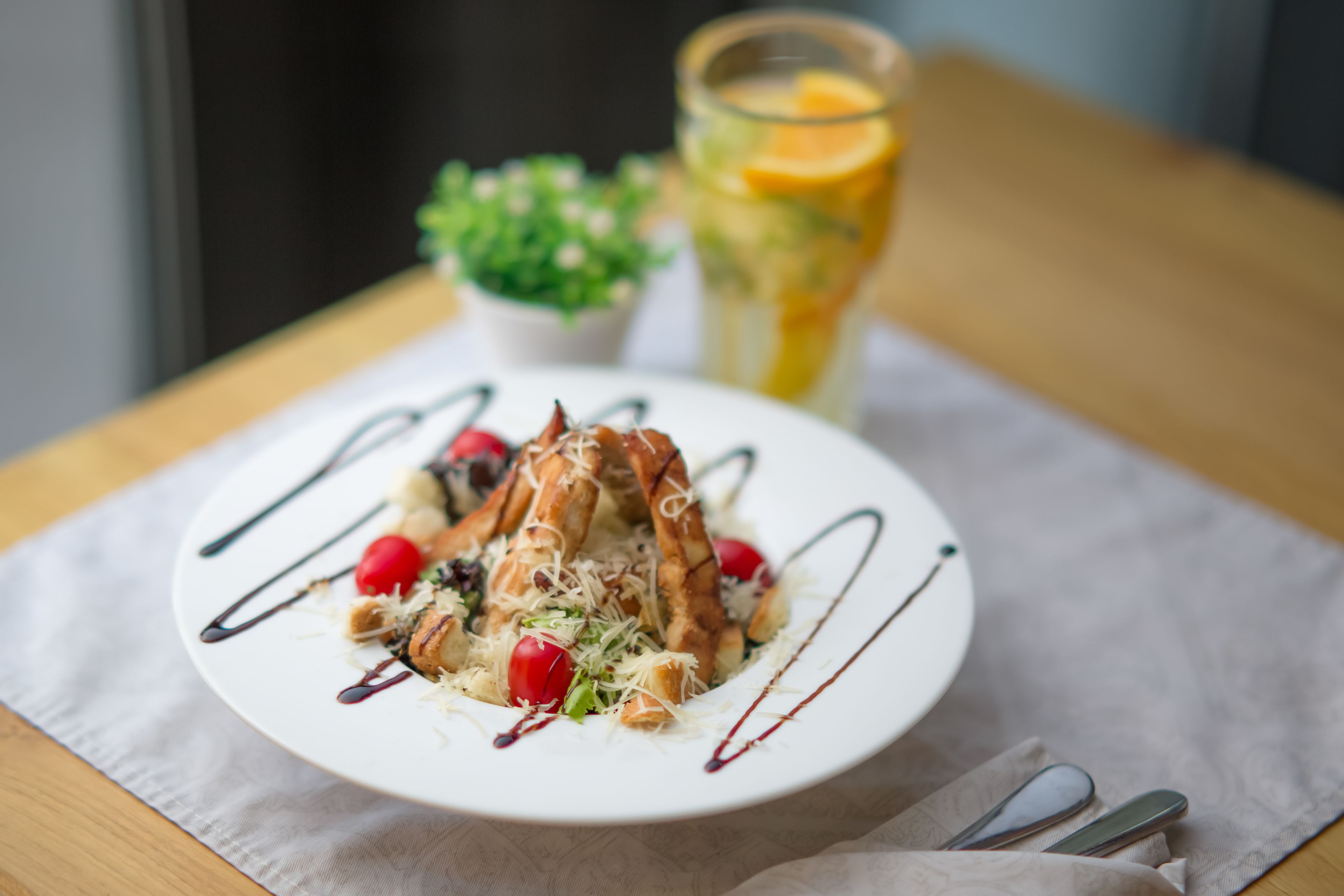 A plate of food with a glass of juice and a small plant on a table.