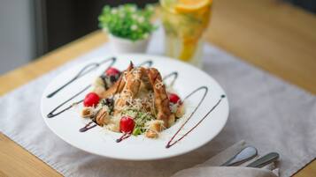 A plate of food with a glass of juice and a small plant on a table.
