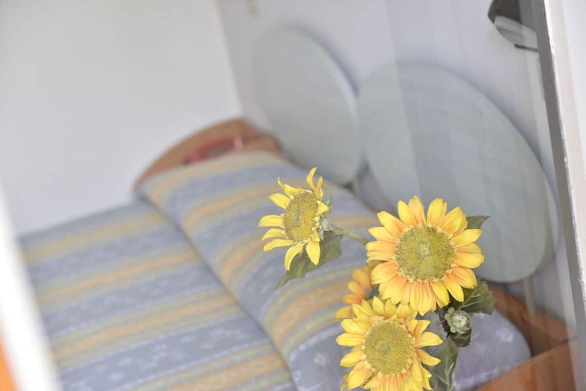 Cama com roupa de cama listrada e um vaso com girassóis.