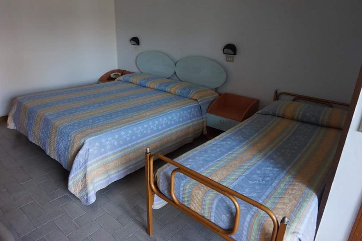 Quarto com duas camas de solteiro, cada uma com cabeceira e mesa de cabeceira.