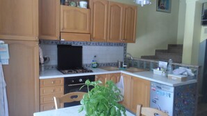 A kitchen with wooden cabinets, a stove, a sink, and a dining table with chairs. - Maison Mare&Monti (Pesaro)