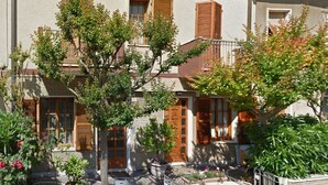 A two-story building with a balcony, wooden shutters, and a garden with potted plants and flowers. - Maison Mare&Monti (Pesaro)