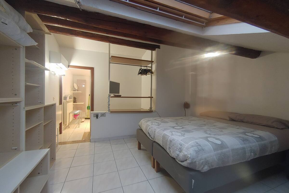 A bedroom with a bed, a mirror, and built-in shelving.