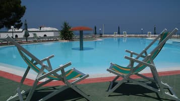 Una piscina al aire libre de temporada, sillones reclinables de piscina