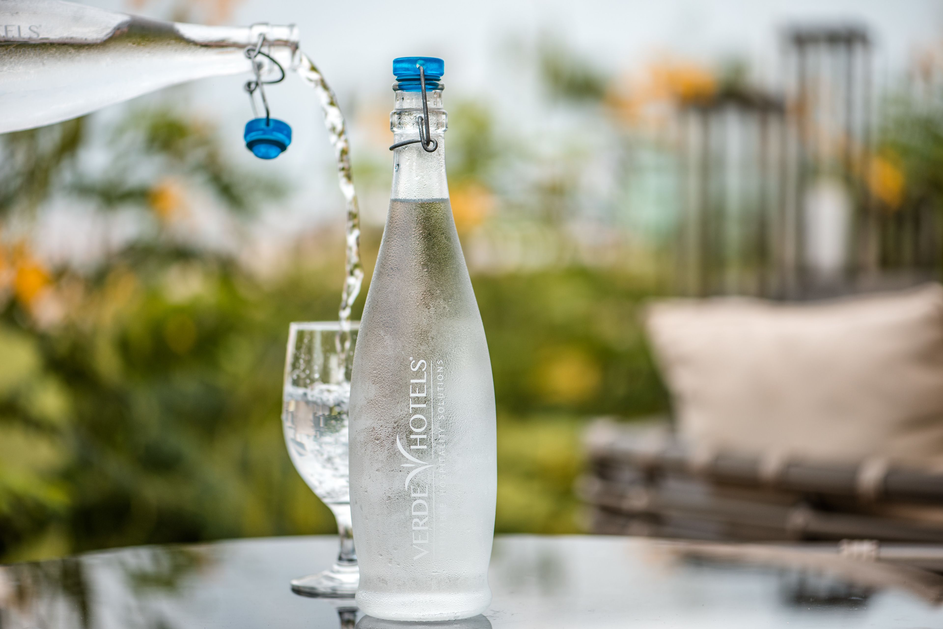 Una botella de agua con etiqueta, sobre una mesa al aire libre.