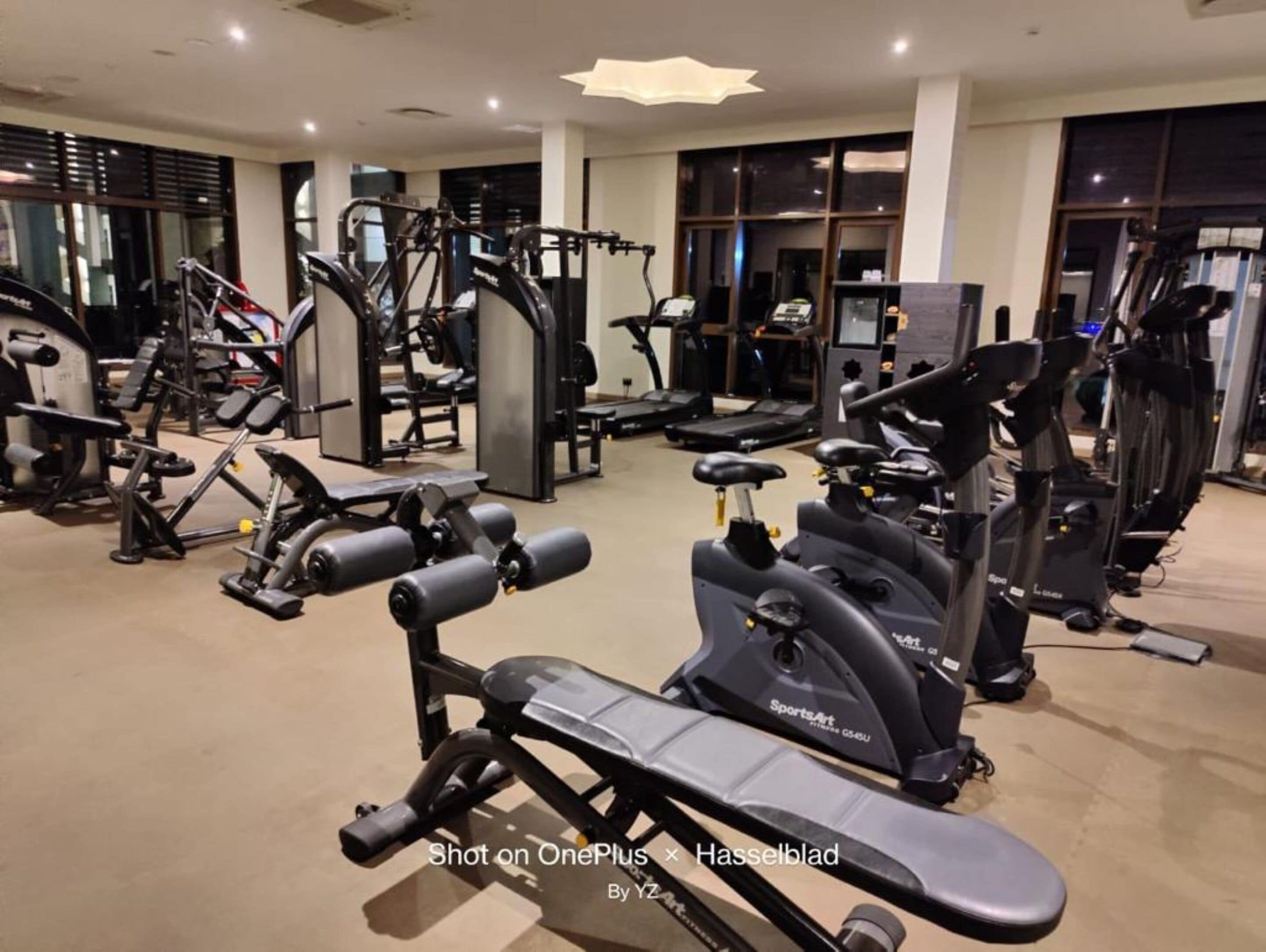 A gym with various exercise equipment including treadmills, elliptical machines, and weight machines.