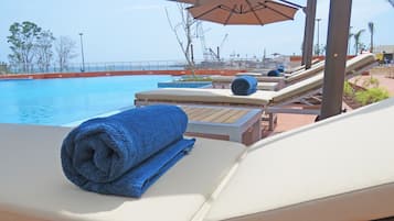 Una piscina al aire libre, sombrillas, sillones reclinables de piscina