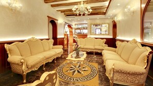 Eine luxuriöse Lobby mit verzierten Sofas, einem Marmorboden und einem Barbereich im Hintergrund.