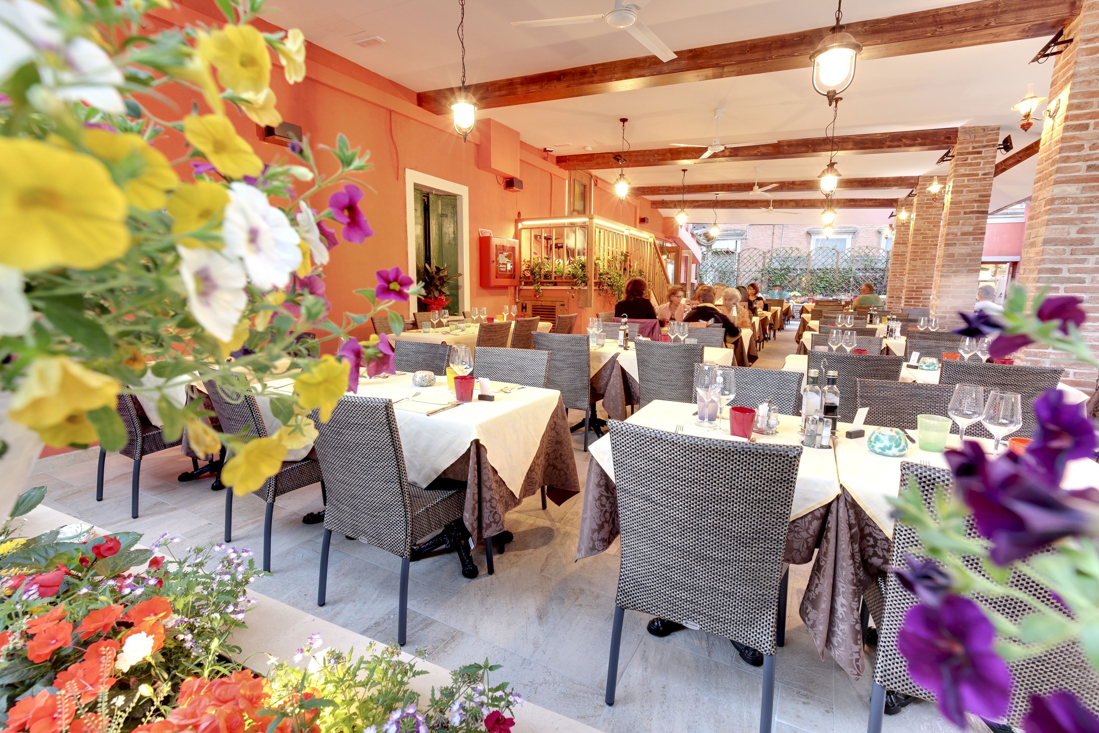 Un espace de restauration intérieur avec des tables disposées pour accueillir plusieurs personnes, agrémenté de chaises en osier et de nappes blanches.