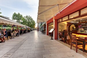 Un caffè all'aperto con tavoli, sedie, un'area bar e una tettoia.