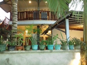 Enjoy the view from the balcony overlooking the lush lower level, surrounded by potted plants and greenery.
