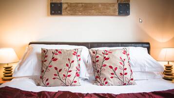 A neatly made bed with two decorative pillows, two bedside lamps, and a rustic wall decoration.