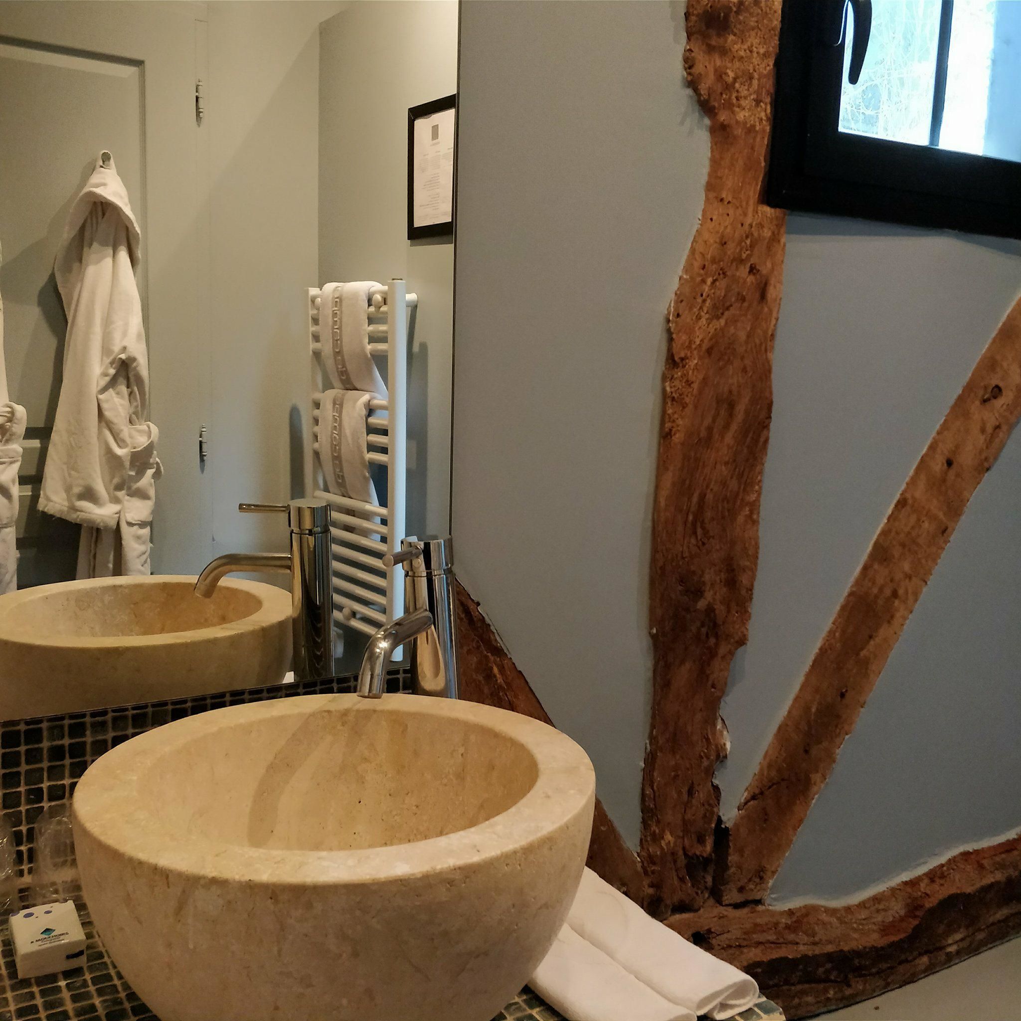 Ein Badezimmer mit zwei großen, beige farbenen Waschbecken, einem Handtuchhalter mit einem weißen Handtuch, einer Zahnbürstenhalterung und einem Spiegel.