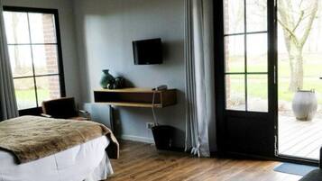 A bedroom with a bed, a television mounted on the wall, a window, and a door leading outside.