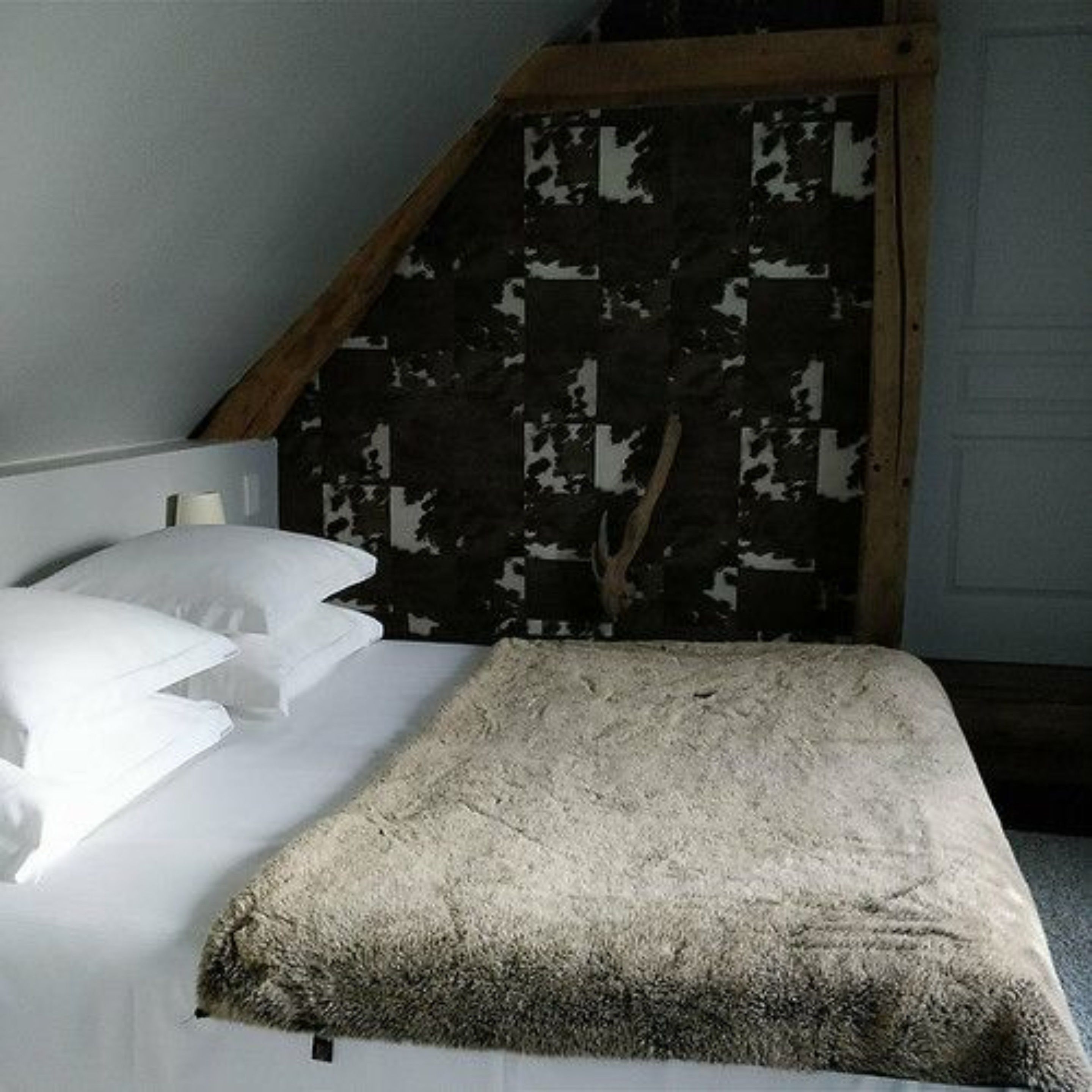 A bedroom with a bed, pillows, and a blanket.