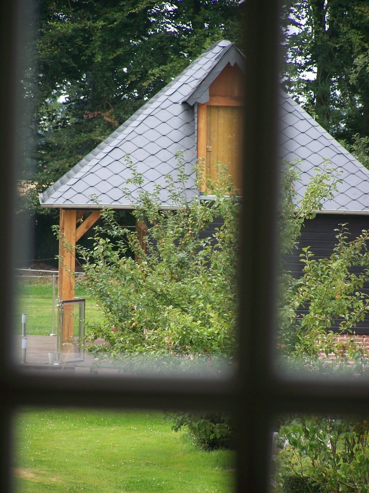 A house with a sloped roof, wooden structure, and a fenced garden area.