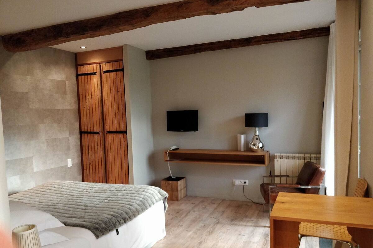 A bedroom with a bed, a desk, a chair, a TV, and a wardrobe.