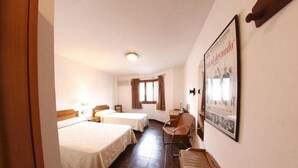 Una habitación de hotel con dos camas, un escritorio, una silla y un cartel en la pared.