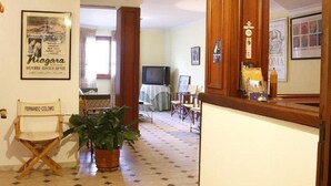 Una sala de estar con televisor, una planta en maceta y un cartel enmarcado en la pared.
