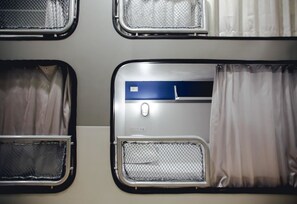 A train carriage interior with multiple compartments, each featuring a window with a mesh screen and curtains. - Tales Khaosan Cafe & Hostel (Bangkok)