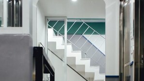 Interior moderno com escada, um banco preto e elevador de vidro.